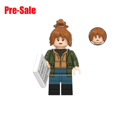 A custom toy minifigure of Jean Grey from X-Men, featuring brown hair in a bun, an olive green jacket over a tan vest, blue pants, and black boots. The figure holds a white communicator device.