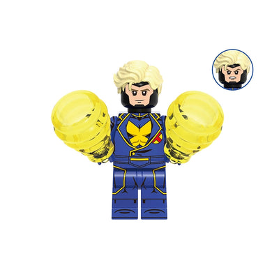 A building block minifigure of Havok from Marvel, featuring a blue and yellow suit, blonde hair, and translucent yellow bionic arm prosthetics. The image includes a gray label at the top with the code 'GHO957' and a circular inset showing an alternate angry face design.