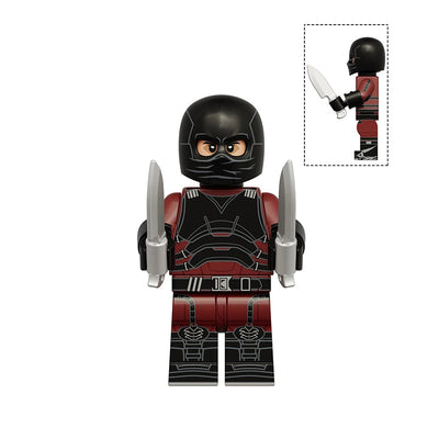 A toy minifigure labeled Tarantula, shown front-facing on a white background with a small inset side view. The figure has a black mask and helmet, a red and black suit with gray wing-like arm pieces, and a small silver sword.